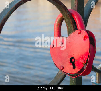 Età rusty bloccato a forma di cuore ad un lucchetto sulla ringhiera di metallo Foto Stock