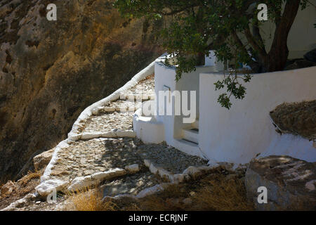 White la cappella dipinta parete sotto la scogliera con passi da sole alberi Foto Stock