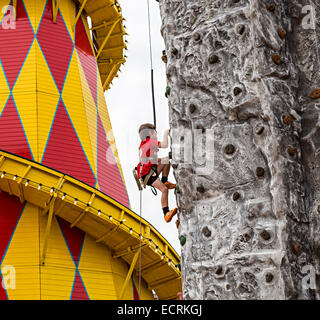 Bambino sulla parete di arrampicata alla fiera del divertimento, Cardiff Bay, Wales, Regno Unito Foto Stock