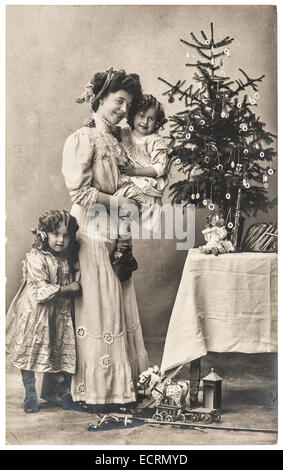 Felice madre e bambini con albero di natale e giocattoli antichi. vintage immagine seppia con pellicola originale del grano e la sfocatura Foto Stock