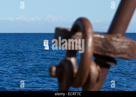 Neve fresca sulle montagne di San Gabriel visto da Avalon, Isola Catalina, California. Un arrugginimento delle navi ancora sfocato in primo piano. Foto Stock