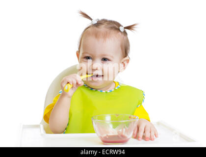 Baby mangiare con il cucchiaio seduta a tavola isolato Foto Stock