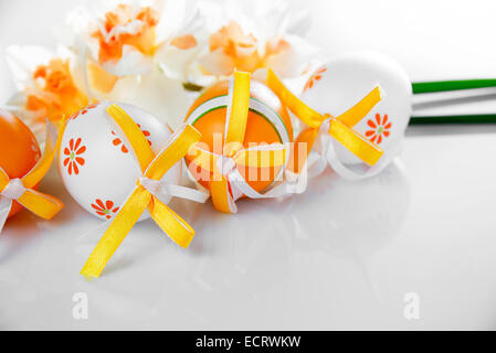 Uova di Pasqua e narcisi su sfondo bianco Foto Stock