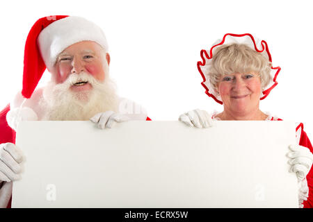 Un ridere Santa e la sig.ra Claus tenere un cartello bianco con un sacco di spazio per il vostro messaggio. Foto Stock