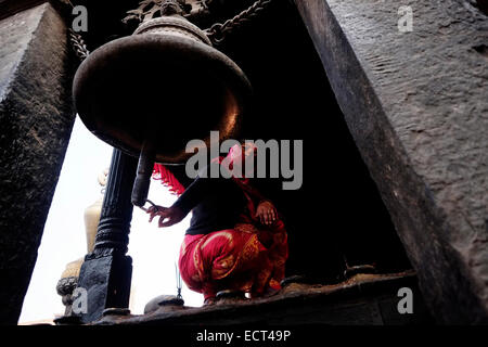 Una donna nepalese suona il campanello del Dattatraya antico tempio costruito durante il regno di Re Yaksha Malla (1428 A.D. - 1482 d.C.) in piazza Dattatrayta nella città di Bhaktapur conosciuta anche come Khwopa in Nepal Foto Stock