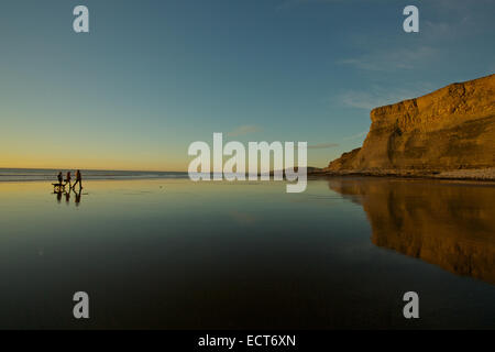 Gli scuotipaglia e il cane a camminare sulla spiaggia vuota durante la serata autunnale, Monknash beach, Patrimonio Costa, Vale of Glamorgan, South Wales, Regno Unito e Unione europea Foto Stock