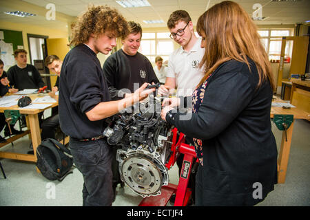 Scuola secondaria di pratica professionale istruzione Wales UK: un insegnante di donna insegnamento anno 12 e 13 6° modulo ragazzi adolescenti circa il motore di una macchina in una ingegneria meccanica classe lezione Foto Stock