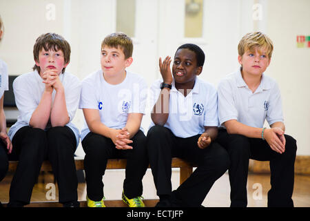 La formazione nella scuola secondaria Wales UK: un gruppo di 9 anno allievi adolescenti guardando gli altri a giocare nella loro scuola gymansium Foto Stock