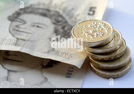Pila di denaro, sterlina monete e £5 note Foto Stock