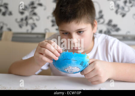 Ragazzo adolescente raccoglie gli enigmi da Globe Foto Stock