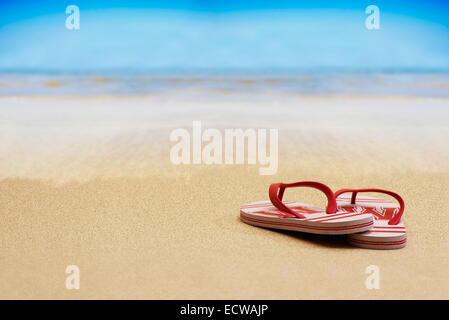 Il flip flop sandali su di una spiaggia di sabbia con cielo blu Foto Stock