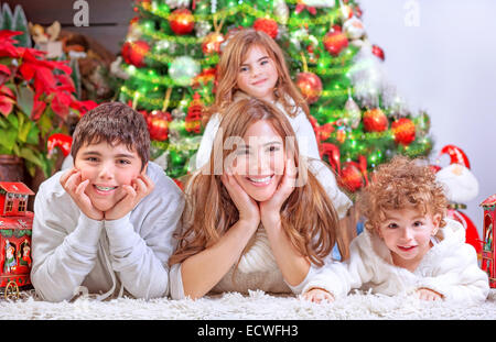Felice Natale celebrazione, allegro famiglia avente il divertimento a casa, sdraiati vicino al bellissimo albero di Natale decorato Foto Stock