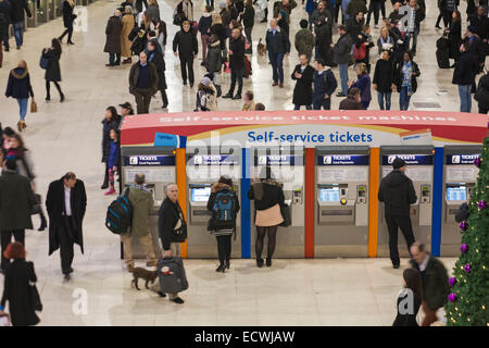 Viaggiatori con biglietti self-service e hurying alla stazione di Waterloo in testa a Natale a Londra Regno Unito nel mese di dicembre Foto Stock