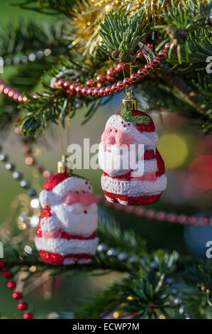 Baubles a forma di Babbo Natale appesi ai rami di un albero di Natale. Foto Stock