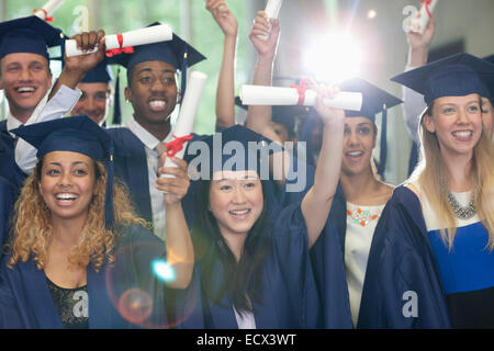 Sorridendo gli studenti universitari in piedi in corridoio con i loro diplomi dopo la cerimonia di consegna dei diplomi Foto Stock
