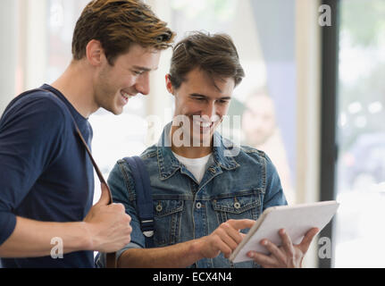 Due gli studenti maschi guardando a tavoletta digitale e ridere Foto Stock