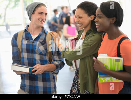 Gli studenti titolari di libri e di ridere con altri studenti in background Foto Stock