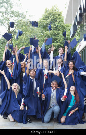 Ritratto di gruppo di studenti di laurea camici mortarboards gettando in aria Foto Stock