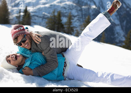 Coppia esuberante che stabilisce nella neve Foto Stock