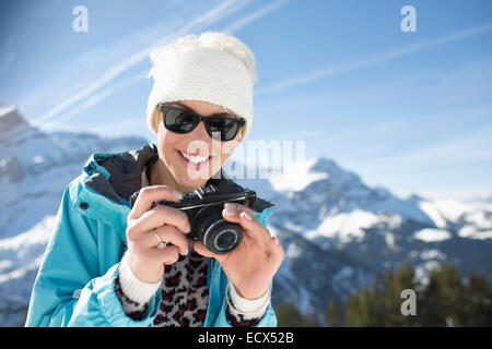 Ritratto di donna sorridente con fotocamera in montagna Foto Stock