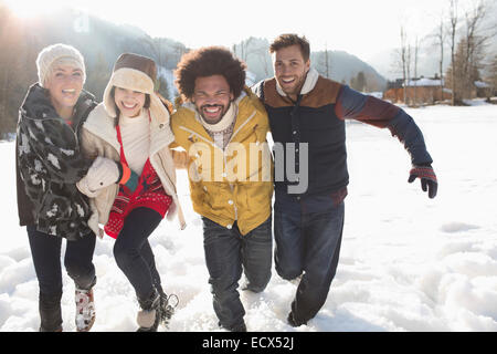 Amici in esecuzione nella neve Foto Stock