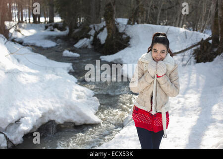 Ritratto di donna sorridente camminando lungo la riva nevoso Foto Stock