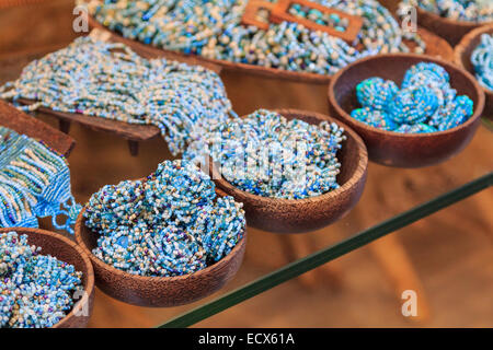 E plastica blu Perline di pietra su un ripiano di vetro in ciotole di legno Foto Stock