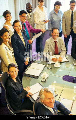 Alta vista angolare di sorridere la gente di affari guardando la fotocamera in sala conferenze Foto Stock