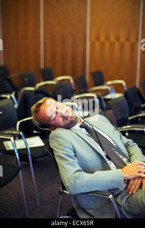 Imprenditore dormire in sala conferenze Foto Stock