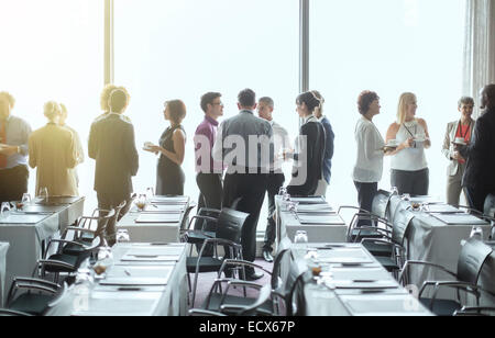 Un gruppo di persone in piedi dalle finestre della sala conferenze, socializzare durante la pausa caffè Foto Stock