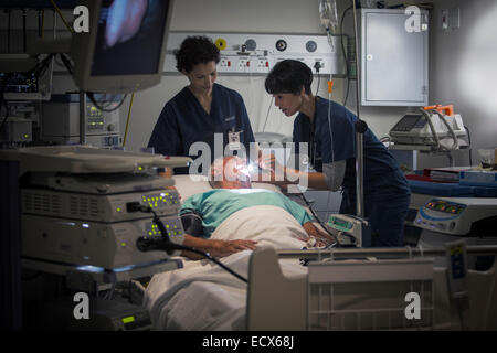 Femmina matura medico e infermiere femmina l'esame del paziente di gola Foto Stock