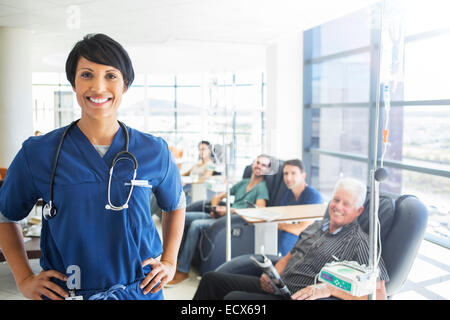 Ritratto di medico con pazienti che ricevono cure mediche in background Foto Stock