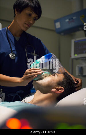 Medico donna che indossa la maschera di anestesia metà uomo adulto in ospedale Foto Stock