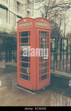Un tradizionale rosso cabina telefonica in un giorno di pioggia a Londra, UK in stile retrò Foto Stock