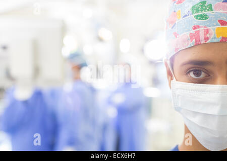 Ritratto di chirurgo mascherato con sfocate impostazione ospedaliera in background Foto Stock