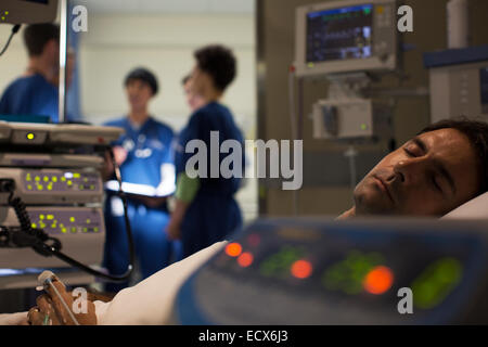 Paziente circondata da medici apparecchiature di monitoraggio nelle unità di terapia intensiva Foto Stock