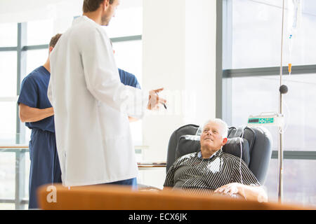 Due medici a parlare con il senior paziente sottoposto a trattamento medico in ambulatorio Foto Stock