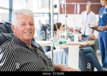 Senior sorridente uomo sottoposto a trattamento medico in ambulatorio Foto Stock