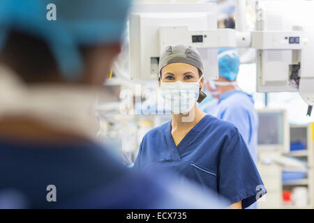 Medico donna che indossa il cappuccio chirurgico e maschera e guardando la fotocamera Foto Stock