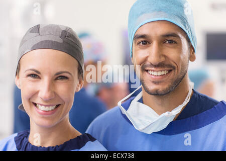Ritratto di sorridere i medici indossano cappucci chirurgica in sala operatoria Foto Stock