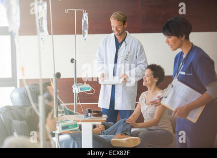 I medici che frequentano i pazienti che ricevono infusione endovenosa in ospedale Foto Stock