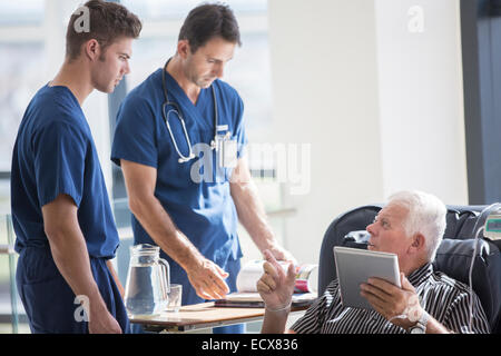 Paziente utilizzando un tablet PC e a parlare con i medici in ospedale Foto Stock