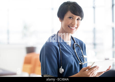 Ritratto di donna medico con stetoscopio attorno al collo, tenendo tavoletta digitale Foto Stock