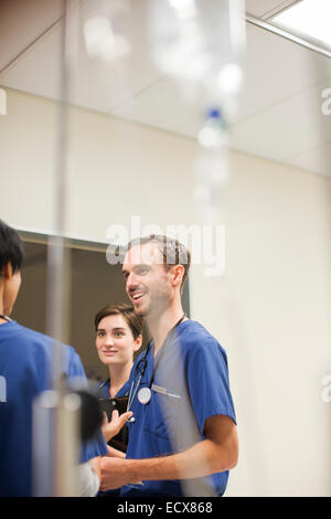 Flebo IV nella parte anteriore dei medici che indossa scrubs parlando in ospedale Foto Stock