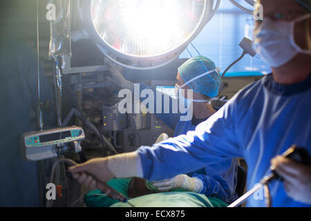 Maschio e femmina ai chirurghi di eseguire la chirurgia laparoscopica nella camera operativa Foto Stock