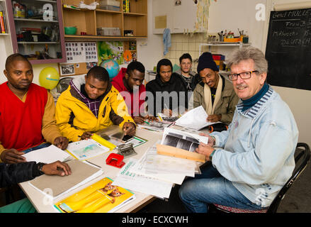 Un pensionato di assistente sociale, lavorando come volontario ora (a destra), dà una lezione in lingua tedesca per la maggior parte dei profughi africani. Foto Stock