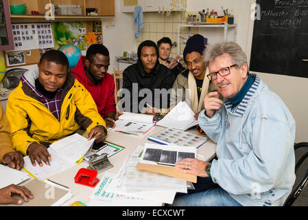 Un pensionato di assistente sociale, lavorando come volontario ora (a destra), dà una lezione in lingua tedesca per la maggior parte dei profughi africani. Foto Stock