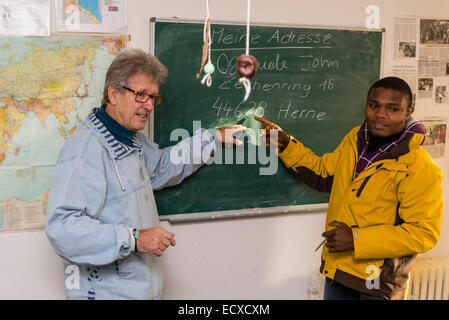 Un pensionato di assistente sociale, lavorando come volontario ora (sinistra), dà una lezione in lingua tedesca per la maggior parte dei profughi africani. Foto Stock