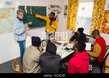 Un pensionato di assistente sociale, lavorando come volontario ora (sinistra), dà una lezione in lingua tedesca per la maggior parte dei profughi africani. Foto Stock
