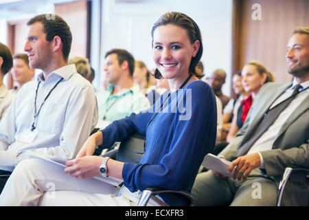 Ritratto di giovane sorridente donna seduta in udienza nella sala conferenze Foto Stock